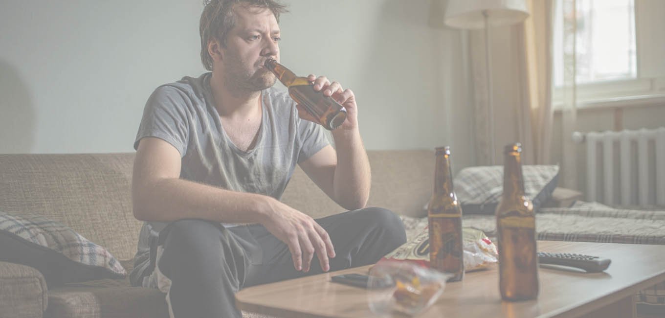 Мужчина пьет пиво сидя на диване